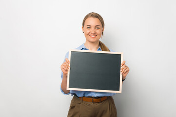 Fototapeta premium Young stylish woman holds blackboard in studio against white background.