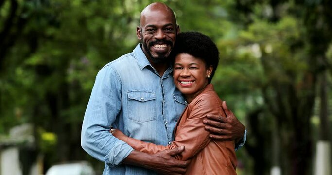 African couple embracing together outside portraits looking at camera standing outside