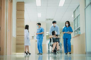 doctor medical team assistant patient who is sitting on wheelchair, explaining prescription to young asian patient, healthcare concept. wearing face mask during covid-19 pandemic.