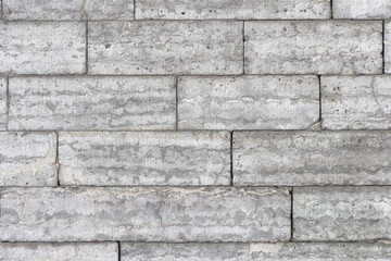 The texture of a gray stone wall made of rectangular marble blocks. Sunlight on the masonry.