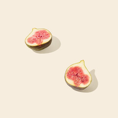 Sunlit halved fig isolated on pastel beige background. Sun and shadows. Organic, raw, natural healthy food concept. Minimal Mediterranean summer fruit scene.