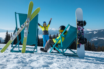 skier and snowboarder sitting on the top of the mountains in chairs enjoying