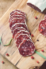 Sliced french salami with fresh rosemary and on rustic wooden background. Close up. 