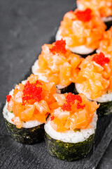 appetizing sushi roll maki with salmon on a black stone plate