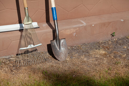 Fan rake and small shovel stand in front of wall