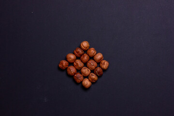 Hazelnut folded in the shape of a diamond, Roasted hazelnuts on a black background. Free space for the inscription.