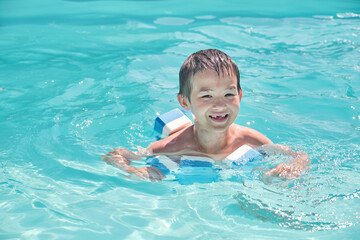 Fototapeta na wymiar Little asian boy is learning to swim in outdoor pool