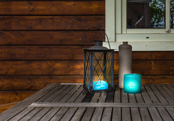 Decorative metal lantern with blue canles glowing on wooden table, vintage stylish design with copy space