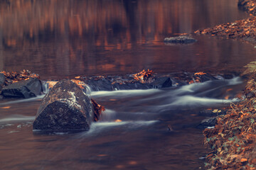 Long exposure of a river in the forest in autumn