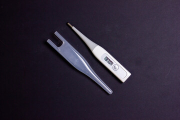 Thermometer on a black background. Household electronic thermometer. Background for the label. The thermometer of a sick person.