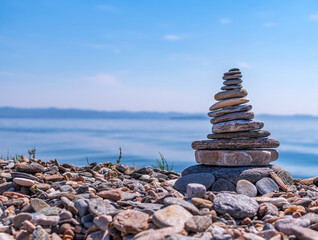 Pyramid of stacked stones on the shore of Lake Baikal at summer sunny day. Close-up..