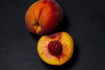 Peaches on a black background. Peach cut in half. Healthy diet.