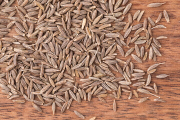 Dried cumin seeds on wooden background, close up, organic food