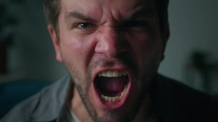 Irritated emotional man shouting close-up, portrait of screaming brutal male person with beard, sitting on sofa in living room, looking in camera with furious view, feeling anger and stress, bad mood. - Powered by Adobe
