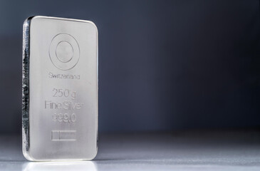 Minted silver bar weighing 250 gram against a blurred dark background.