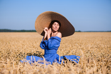 Naklejka na ściany i meble Girl in wide brim hat in wheat