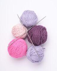 Colorful yarn balls and knitting needles on white background