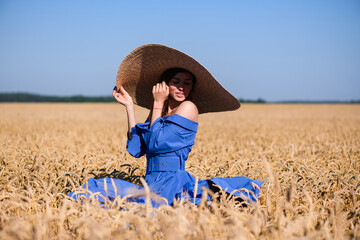 Naklejka na ściany i meble Woman in wide brim hat in wheat