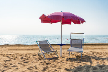 Sunbeds and parasol beach umbrella during a sunny beach holiday in Italy
