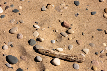 Fototapeta na wymiar Lake Michigan created the mosaic of beach sand, mulit-colored stones, driftwood and foot prints in the beach at Kohler-Andrae State Park, Sheboygan, Wisconsin in mid-March