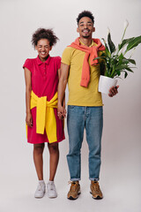Happy woman holds her boyfriends hand. Man posing with plant. Cheerful brunette guy in jeans and...