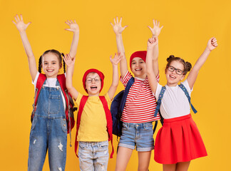 Fototapeta premium Group of happy schoolkids with backpacks and with arms raised