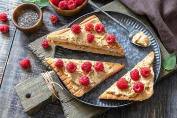 Summer sweet dessert sandwich breakfast. Tasty toasted with peanut butter and raspberry on a rustic wooden table.