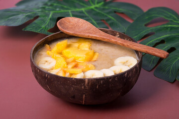 smoothie in coconut bowl with monstera leaves. Healthy life clean eating concept.