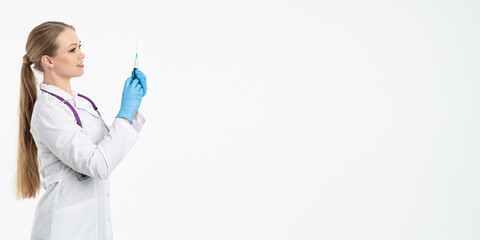 A young nurse in a mask and white coat holds a syringe with a needle for injections, flu shots, covid. The concept of vaccination and protection against influenza, from a pandemic. copy space. banner