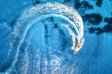 Aerial view of the speed boat in clear blue water at sunny day in summer. Top view from drone of...