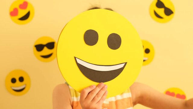 World Smile Day. A little girl with a smiley face changes her emotions. Funny, sad and loving emojis. Anthropomorphic Smiley Face. 