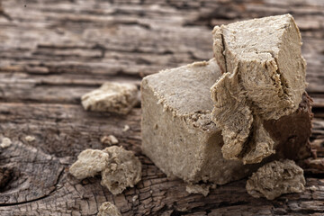 Piece of Halva on brown wooden texture.Traditional eastern dessert on beige background. Horizontal close-up image.