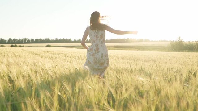 Girl in a dress in a wheat field at sunset