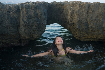 young happy and attractive Asian woman in the sea - cheerful and carefree Chinese girl playful in the water during Summer holidays trip in beautiful tropical island