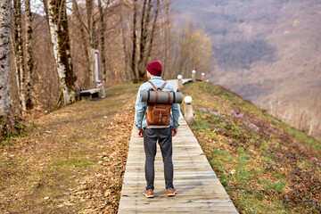 Man hiker exploring mountains, Travel healthy lifestyle adventure trip hiking solo with backpack, male on active vacations outdoors. travel alone. rear view guy in denim jacket stand in contemplation