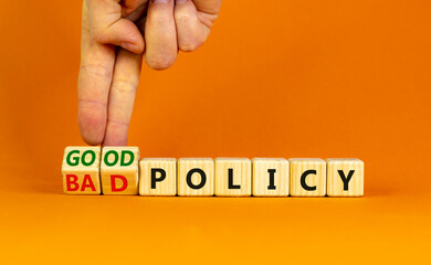 Good or bad policy symbol. Businessman turns wooden cubes and changes words 'bad policy' to 'good policy'. Beautiful orange table, orange background. Business, bad or good policy concept. Copy space.