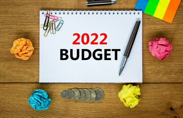 2022 budget new year symbol. White note with words 2022 budget on beautiful wooden table, colored paper, colored pencils, paper clips, coins. Business and 2022 budget new year concept.