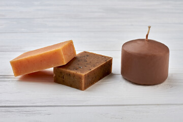 Homemade spa soap bars and candle on white wood.