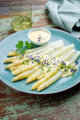 Modern style traditional steamed white asparagus garnished with sauce hollandaise and herbs served...