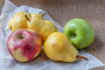 ripe juicy apples and pears on sackloth on white parchment