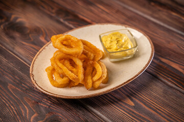 onion rings in breading lie on a plate with tomato sauce, photo for the menu