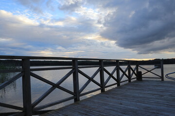Fototapeta na wymiar Beautiful view at a Swedish sea or lake. Wooden fence and bridge. Plenty of bugs. Concept of calmness or solitude. Multicolored sky with plenty of clouds. Stockholm, Sweden, Scandinavia, Europe.