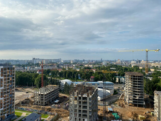 A view from a height of a large modern construction site of tall large houses and multi-storey buildings. A construction site for the development of a new microdistrict in a big city