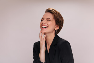 Girl in black jacket laughing on isolated background. Close-up inside portrait of woman in dark suit smiling and posing on white backdrop