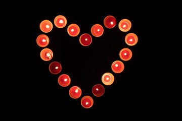 Red burning candles in the shape of a heart on a black background. Valentine's day concept. Top view.