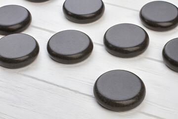 Close-up black polished round stones on white wooden desk.