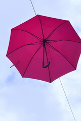 Pink farbiger Regenschirm vor blauem Himmel