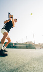 Man training paddle tennis on an outdoor green paddle tennis court behind the net with his coach