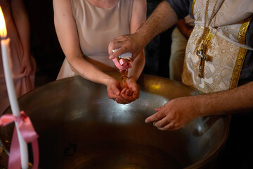 baptismal font with oil and closeup hands