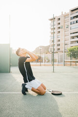 Angry paddle tennis player regretting losing the match on the green court at sunset